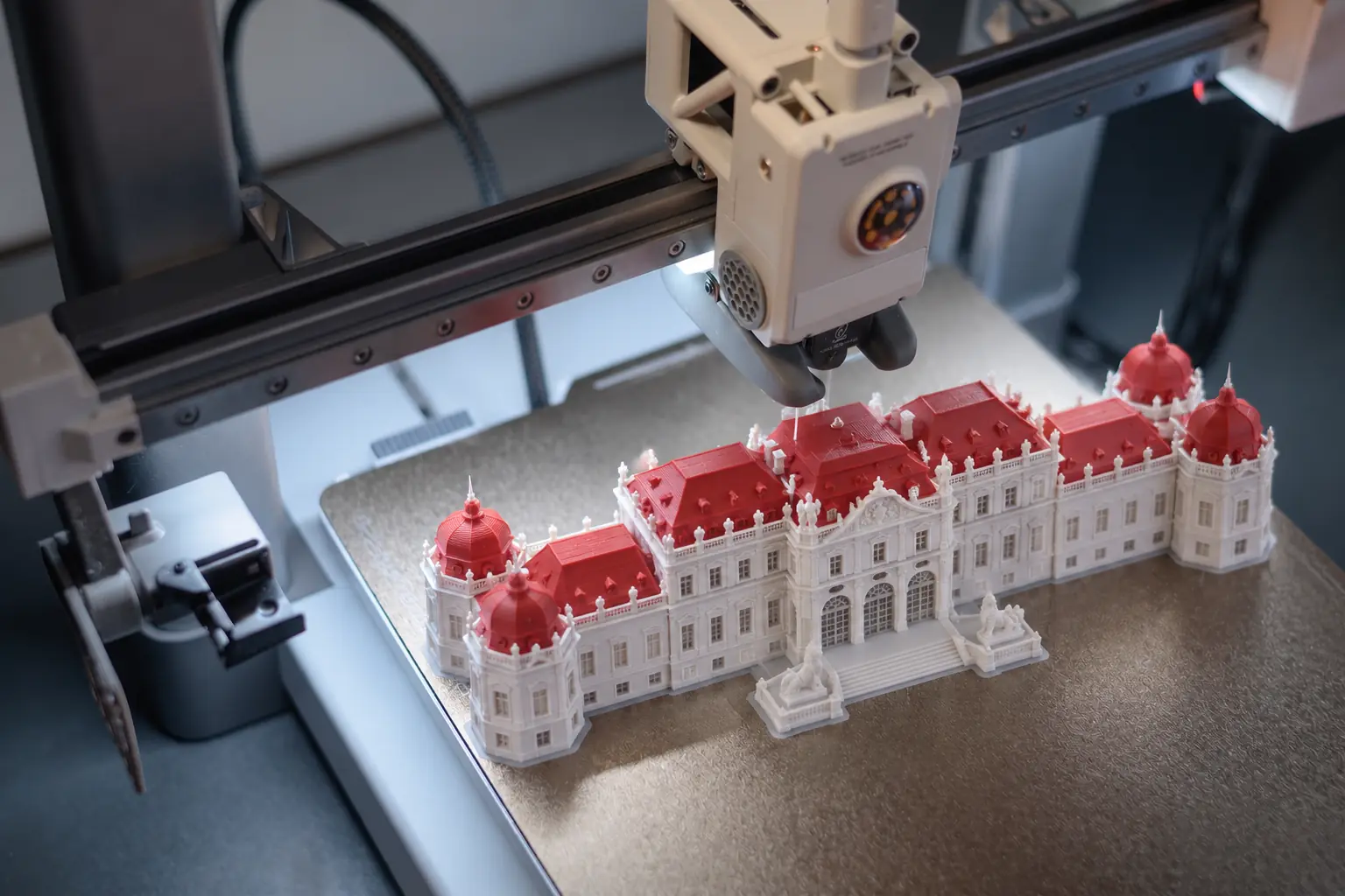 3D-Drucker druckt ein Modell des Schlosses Belvedere in Wien aus weißem und rotem Filament